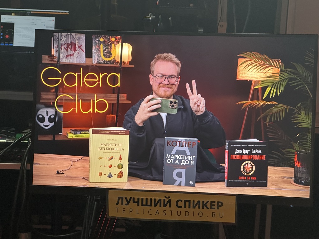 Антон Власов в студии с книгами по маркетингу на столе — про то, какую бухгалтерию для ИП выбрать: софт, аутсорс или штатный бухгалтер