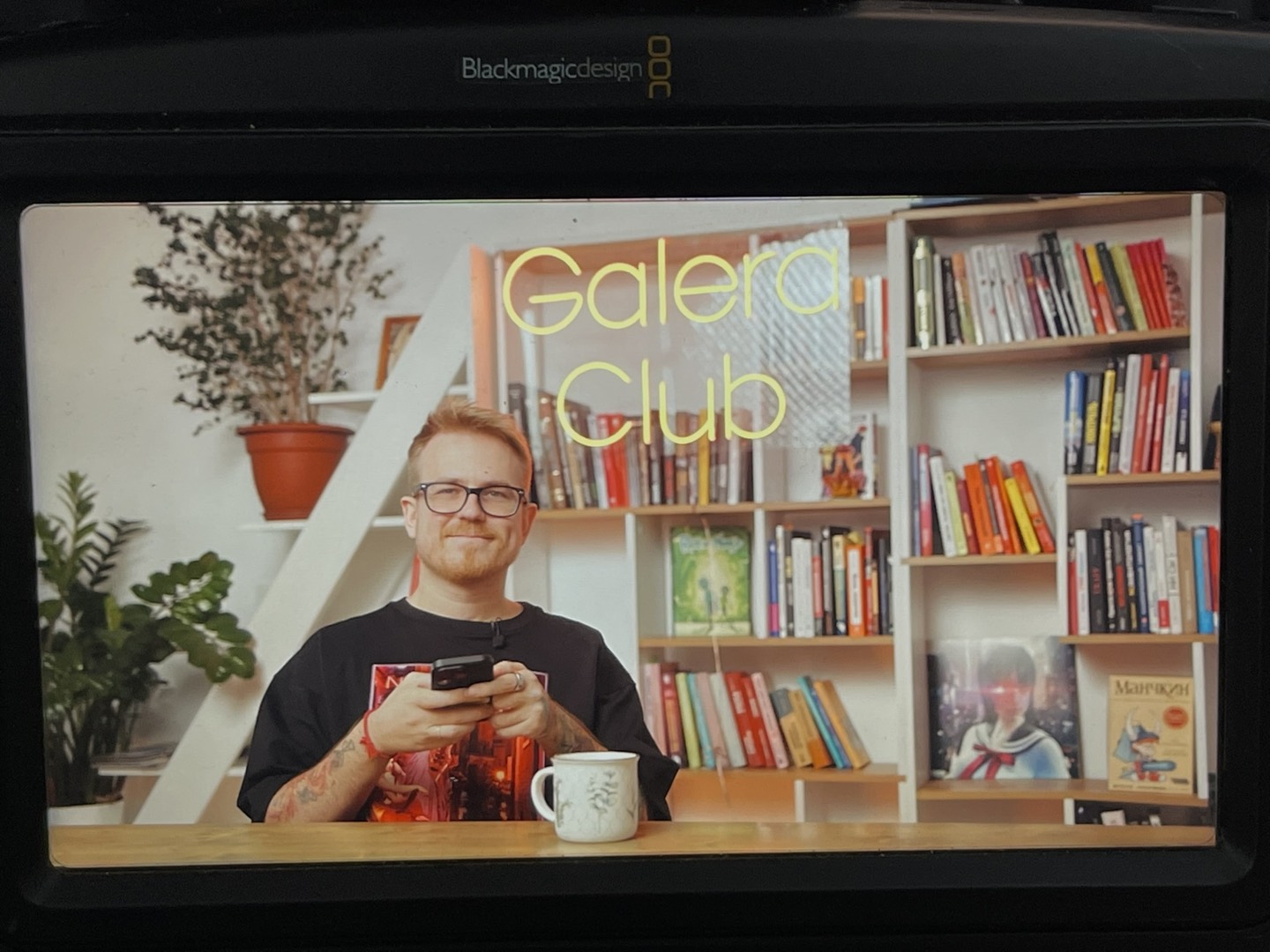 Антон Власов с телефоном на фоне книжного стеллажа в студии Galera Club — про клиентскую базу, которую нельзя держать в одной голове
